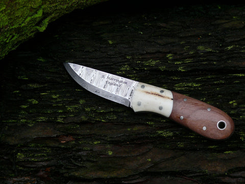 This necker measures 60mm in the blade (2.8mm thick) and over all length at 135mm. The blade steel is Odins Eye Damasteel with a 27 degree scandi grind.The Sambar Stag bolsters and stabilised apple-wood scales are held on with nickel silver pins and are complemented with a nickel silver thong tube. Presented in an oak tanned neck pouch.